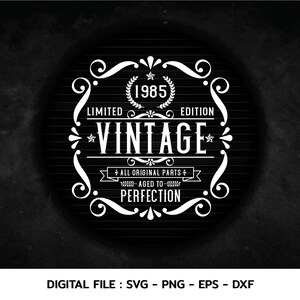 Può includere: Un design vintage bianco su sfondo nero. Il design presenta uno stendardo con il testo "1985 Edizione limitata Vintage Tutti i pezzi originali Invecchiato alla perfezione".