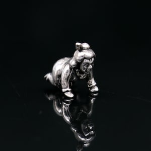 May include: A silver-toned figurine of a baby crawling on a reflective black surface. The baby is wearing a long-sleeved outfit and has a bow in their hair. The figurine is highly detailed and has a polished finish.