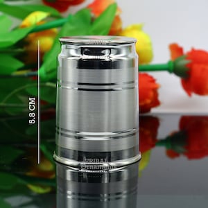 May include: A silver stainless steel container with a smooth, brushed finish and a slightly rounded top. The container has three horizontal bands around the middle. The container is 5.8 inches tall. The container is labeled "Tribal Ornaments".