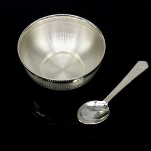 May include: A silver bowl and spoon set. The bowl is round and has a smooth, shiny surface. The spoon has a decorative handle.