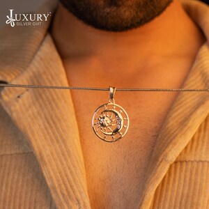 May include: A silver necklace with a pendant featuring a sun and moon design. The pendant is circular and has a detailed design of the sun and moon.