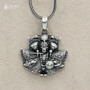 May include: A silver pendant necklace featuring a detailed depiction of a deity with intricate designs and a silver chain.