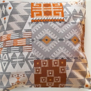 Könnte beinhalten: Ein quadratisches Kissen mit einem geometrischen Muster in Braun-, Orange- und Grautönen. Das Kissen hat ein Patchwork-Design mit verschiedenen geometrischen Formen und Mustern.