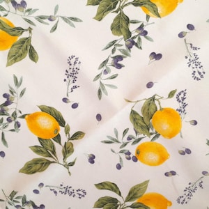 Könnte beinhalten: Ein weißes quadratisches Tischtuch mit einem sich wiederholenden Muster aus gelben Zitronen, grünen Blättern und lila Lavendelzweigen. Die Zitronen sind leuchtend gelb und die Blätter sind tiefgrün. Der Lavendel fügt dem Design einen Hauch von Lila hinzu.