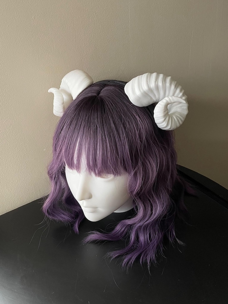 3D printed white ram horns mounted to a black headband displayed on a mannequin
