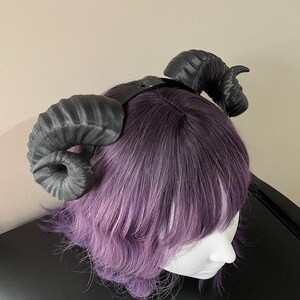 3D printed black ram horns mounted to a black headband displayed on a mannequin