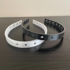 A semi clear and black headband featuring multiple screw holes for mounting horns and ears