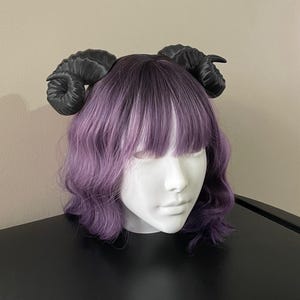 3D printed black ram horns mounted to a black headband displayed on a mannequin