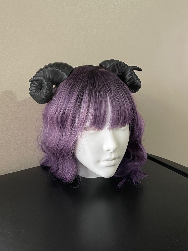 3D printed black ram horns mounted to a black headband displayed on a mannequin