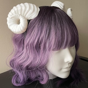 3D printed white ram horns mounted to a black headband displayed on a mannequin