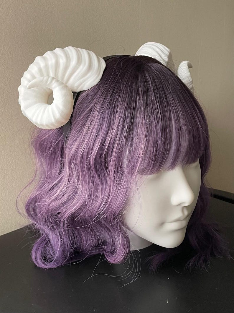 3D printed white ram horns mounted to a black headband displayed on a mannequin