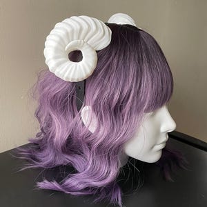 3D printed white ram horns mounted to a black headband displayed on a mannequin