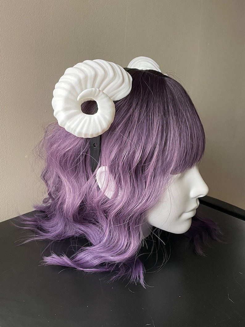 3D printed white ram horns mounted to a black headband displayed on a mannequin