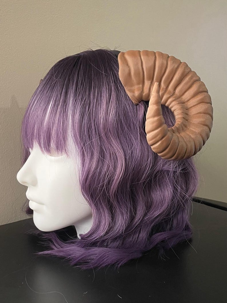 3D printed dark brown Nordic Ram Horns mounted to a black headband displayed on a mannequin