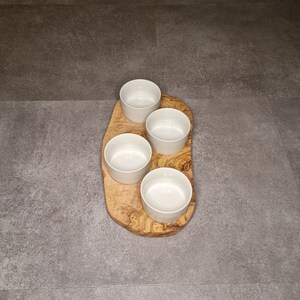Puede incluir: Cuatro cuencos de cer&aacute;mica blanca sobre una bandeja de servir de madera. La bandeja est&aacute; hecha de madera de olivo y tiene un patr&oacute;n de veta natural.
