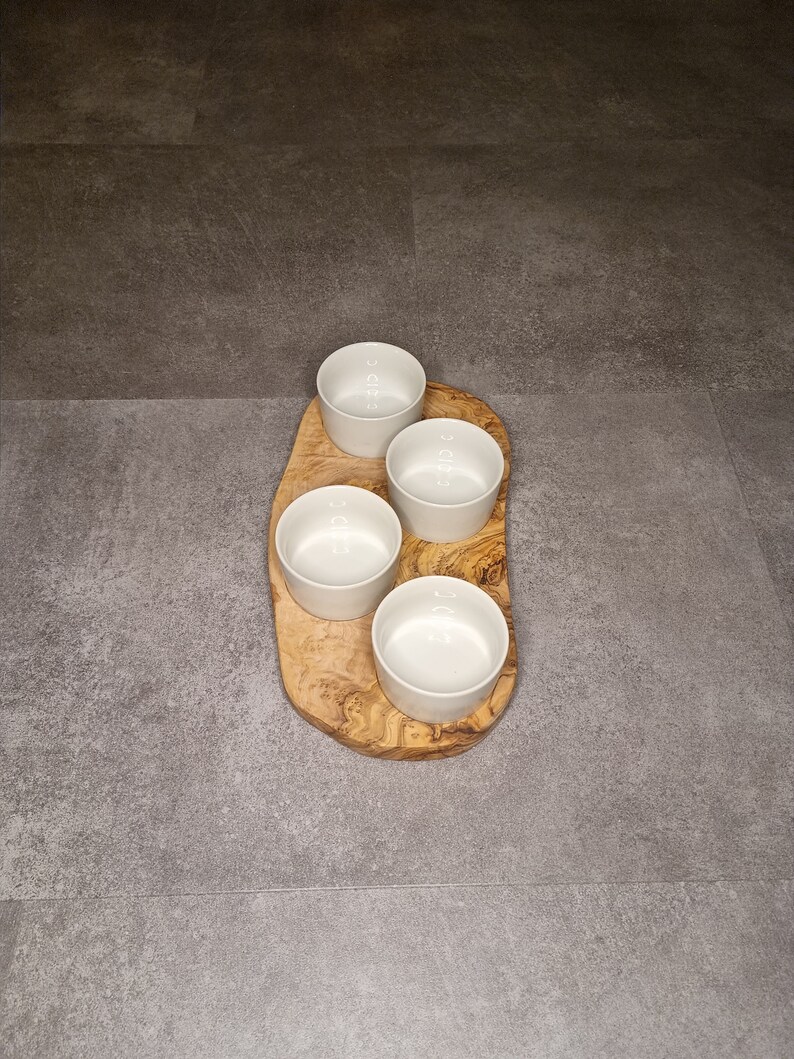 Puede incluir: Cuatro cuencos de cer&aacute;mica blanca sobre una bandeja de servir de madera. La bandeja est&aacute; hecha de madera de olivo y tiene un patr&oacute;n de veta natural.