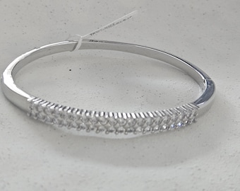 May include: A silver-toned bangle bracelet with a row of small, clear gemstones set across the front. The bracelet has a simple, elegant design, suitable for everyday wear or special occasions. The gemstones sparkle, adding a touch of glamour.