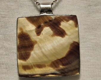 May include: A silver chain necklace with a square pendant featuring a brown and white agate stone.