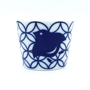 Peut inclure: Une tasse en céramique blanche avec un motif géométrique bleu et blanc et une silhouette bleue d'un oiseau.