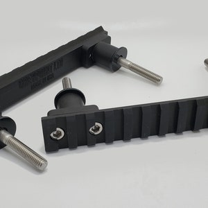 May include: Black, rectangular components with threaded metal rods. The components have a ridged surface and are labeled "TANGENT LTD MADE IN USA". The items are likely hardware or mechanical parts.