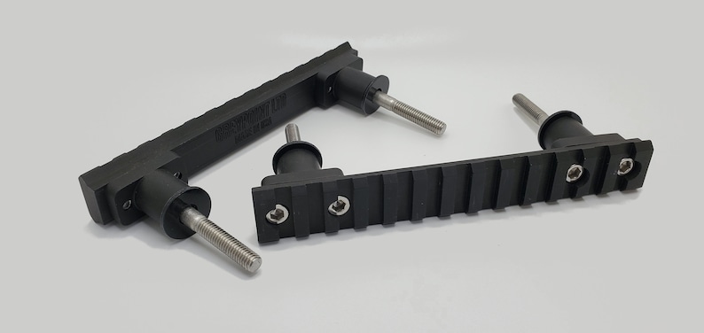 May include: Black, rectangular components with threaded metal rods. The components have a ridged surface and are labeled "TANGENT LTD MADE IN USA". The items are likely hardware or mechanical parts.