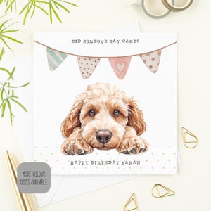 May include: A birthday card with a watercolour illustration of a light brown dog. The card reads "Did someone say cake?" above the dog and "Happy Birthday Sarah" below. The design includes bunting in pastel colours. A cute card for a dog lover.
