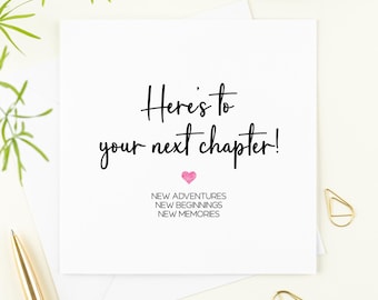 May include: A white greeting card with the text "Here's to your next chapter!" in black script. A pink heart is below the text, with "NEW ADVENTURES, NEW BEGINNINGS, NEW MEMORIES" printed below. Gold paper clips and a pen are visible.