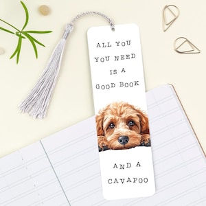 May include: White bookmark featuring a brown and white Cavapoo dog peeking over the top. The bookmark has the text "All you need is a good book and a Cavapoo" printed on it.
