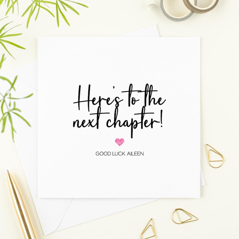 K&ouml;nnte beinhalten: Eine wei&szlig;e Karte mit schwarzer Kalligraphie, auf der "Here's to the next chapter!" steht, mit einem rosa Herzen und dem Text "Good Luck Aileen" darunter.