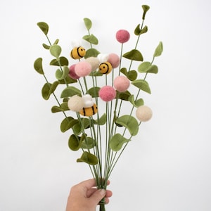May include: A bouquet of felt eucalyptus stems with pink and cream felt balls and yellow and black felt bees.