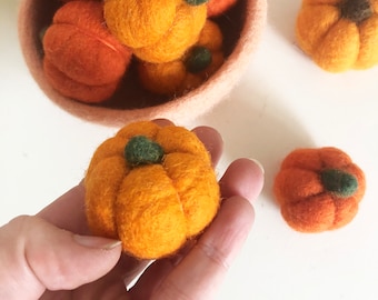 May include: A collection of felt pumpkins in various shades of orange and brown. The pumpkins are handmade and have a rustic, autumnal feel.