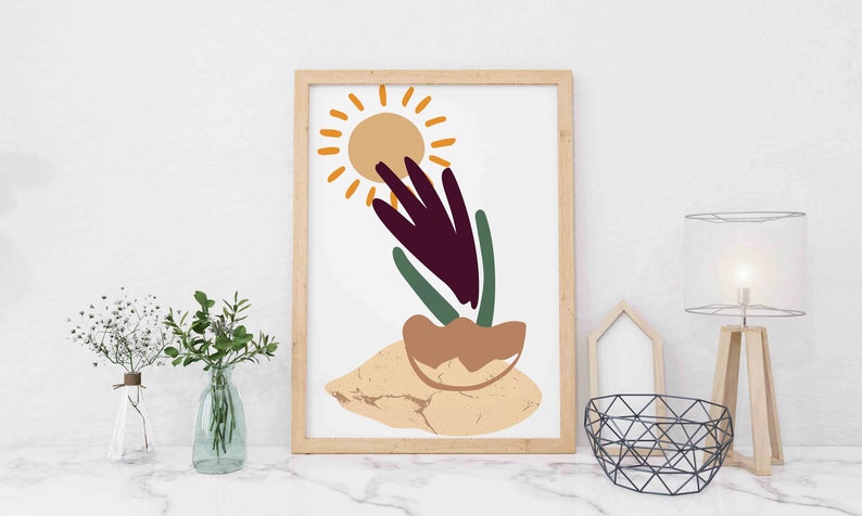 May include: A framed print with an abstract design featuring a stylized sun, a purple flower, and green leaves. The background is a light beige color.