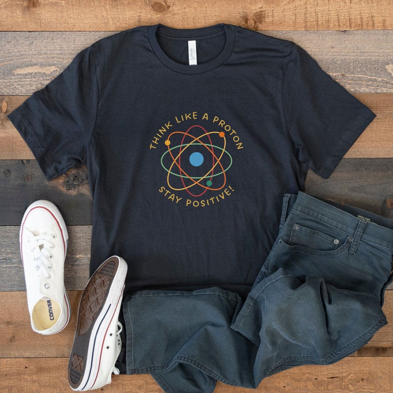 May include: A black t-shirt with a graphic of an atom and the text "Think like a proton, stay positive!"