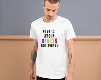 May include: White t-shirt with the text "LOVE IS ABOUT HEARTS NOT PARTS" in black with the word "HEARTS" in rainbow colors.