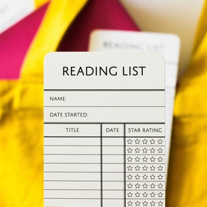 Close up of a paper bookmarks that say Reading List and has room for the reader's name, the date, and the titles of the books they've read, plus a review of each book out of 5-stars.