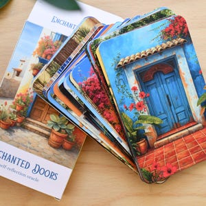 May include: An oracle deck titled "Enchanted Doors" with a stack of cards featuring colourful illustrations of doors and floral arrangements. The box and cards are on a wooden surface. The cards have rounded corners.