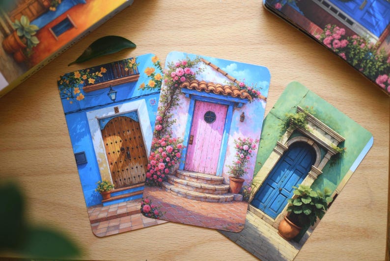 May include: Three art prints depicting doors with floral decorations. One shows a blue door with a wooden door, another a pink door with a tiled roof, and the last a blue door with a stone archway.
