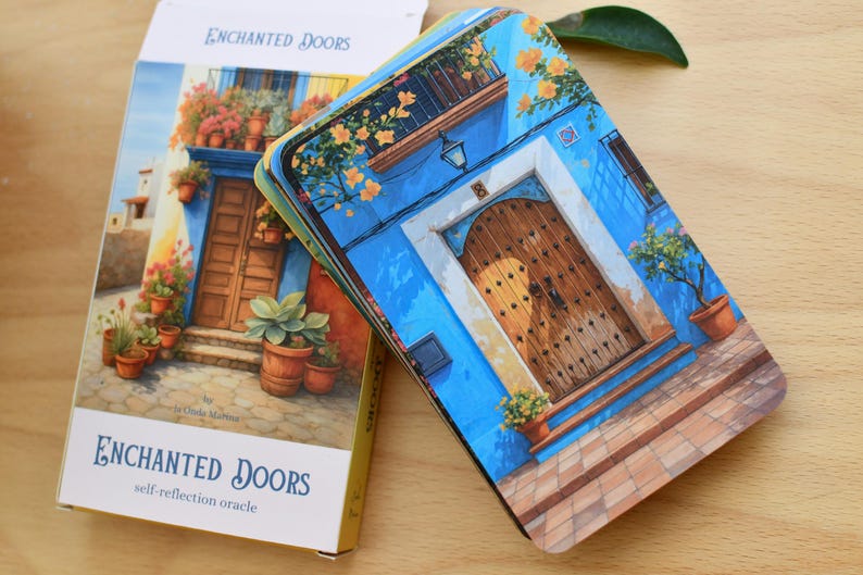 May include: A deck of "Enchanted Doors" self-reflection oracle cards. The cards and box feature a watercolour illustration of a blue building with a wooden door, flowers, and potted plants. The box has the text "Enchanted Doors".