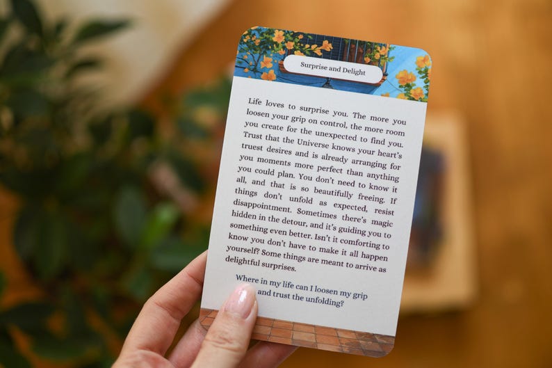May include: A card with the text "Surprise and Delight" and a message about life's surprises. The card has a floral design at the top and is held by a person. The background is blurred.