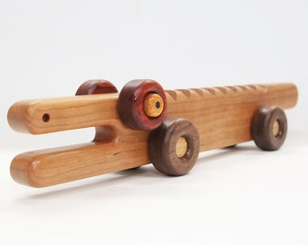 May include: A wooden toy crocodile with brown, red, and yellow wheels. The crocodile is made of light wood and has a carved mouth.
