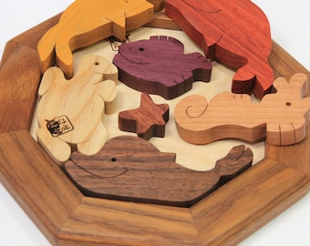 May include: A wooden puzzle featuring various sea creatures, including a whale, a shark, a dolphin, a seahorse, and a starfish. The puzzle pieces are made of different colored wood and fit together to form a complete picture.