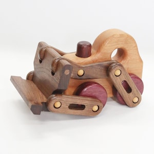 Op de afbeelding: Een houten speelgoed bulldozer met een bruin lichaam, een rood wiel en gele accenten. De bulldozer heeft een beweegbare blad en een werkend stuurwiel.