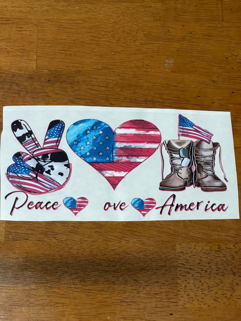 Peut inclure: Graphique Paix, amour et Am&eacute;rique avec un signe de paix, un c&oelig;ur avec un drapeau am&eacute;ricain et une paire de bottes avec un drapeau am&eacute;ricain.