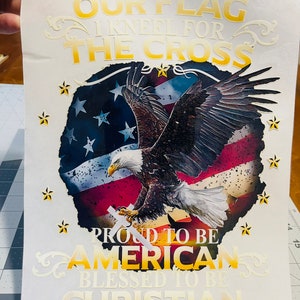 Peut inclure: Un fond blanc avec un design graphique or et blanc repr&eacute;sentant un aigle chauve am&eacute;ricain avec un drapeau am&eacute;ricain en arri&egrave;re-plan. Le texte dit "I will always stand for our flag I kneel for the cross Proud to be American Blessed to be Christian".