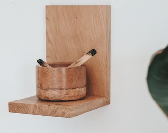 May include: A wooden wall shelf with a small wooden bowl and two wooden sticks. The shelf is mounted on a white wall. *each packet comes with a little gift*
