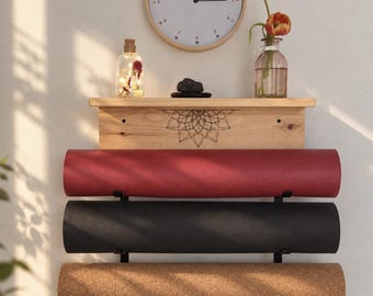 May include: A wall-mounted wooden shelf with a black mandala design, holding three rolled yoga mats in red, black, and cork textures. Above the shelf sits a round wall clock, a clear glass bottle with fairy lights, and a glass vase with orange tulips.