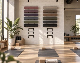 May include: Two vertical wall-mounted racks holding multiple rolled yoga mats in various colours including pink, purple, blue, green, beige, and black. The racks are installed on a white brick wall above black yoga mats on a wooden floor.