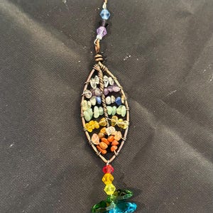 May include: A rainbow crystal suncatcher with a leaf-shaped design and a crystal teardrop pendant. The suncatcher is made with copper wire and features a variety of colored crystals.