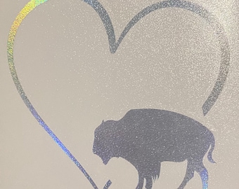 May include: A silver glitter heart with a silhouette of a bison inside. The heart is outlined in black.