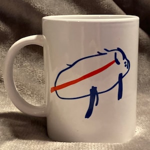 May include: White ceramic coffee mug with a hand-drawn illustration of a blue pig with a red leash.